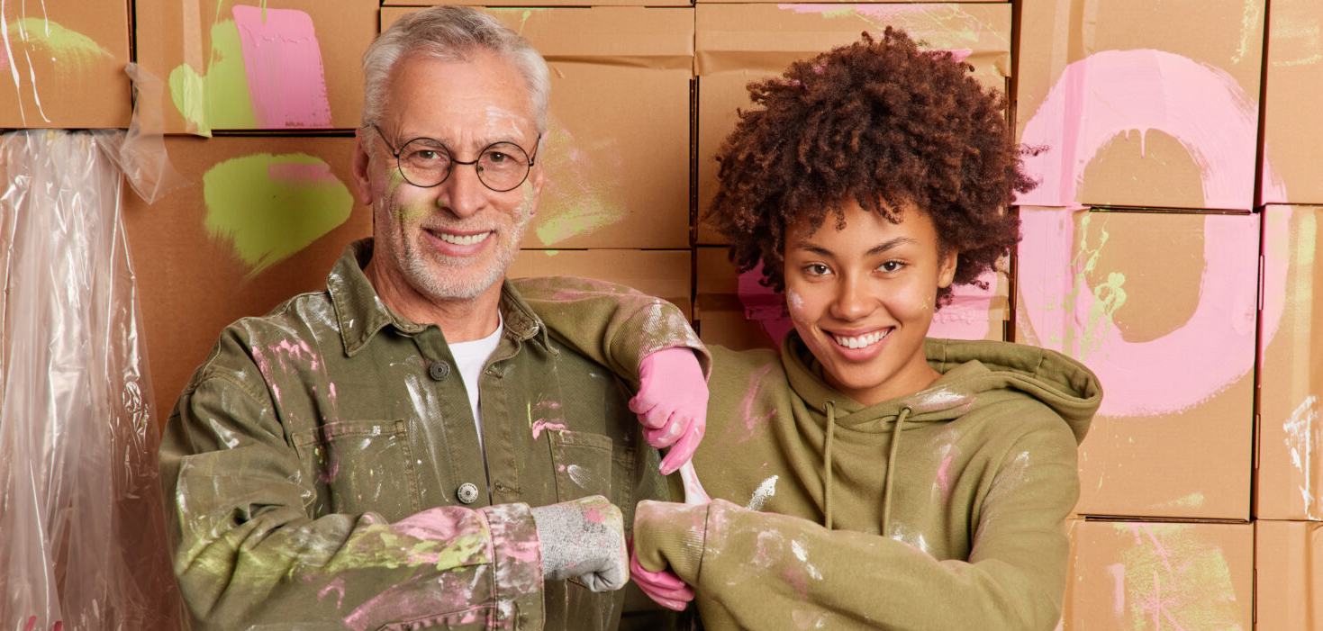 Interracial woman and man make fist bump happy to finish painting walls at home have happy expressions renovate house together. Mixed race repairers work as team. Renewal and repairing concept
